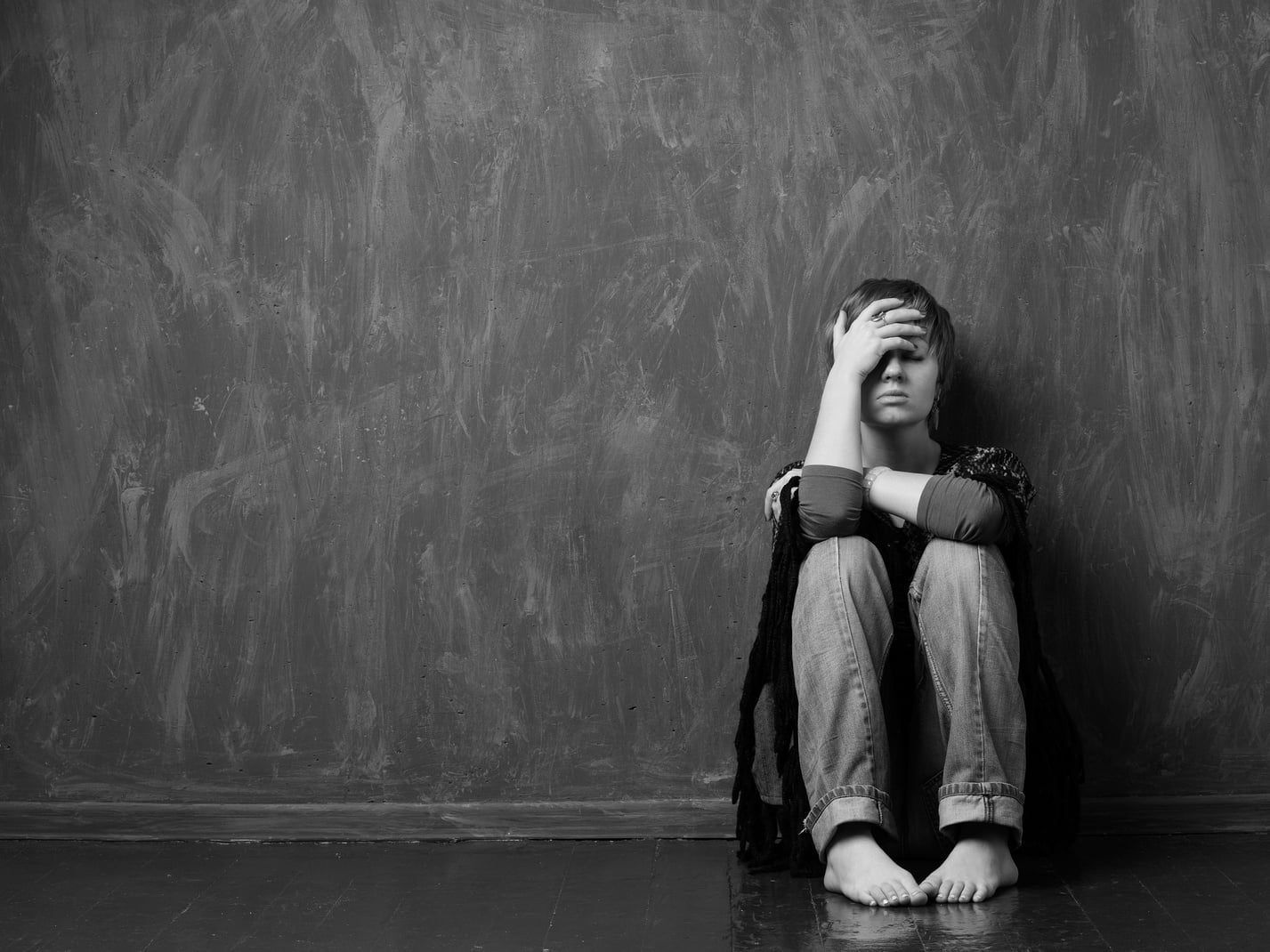 hopeless woman is sitting against the wall